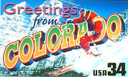 Colorado Greeting: A male skier in red plunges down a snowy slope on the right, against a backdrop of two mountains in Aspen, a popular Colorado ski resort.